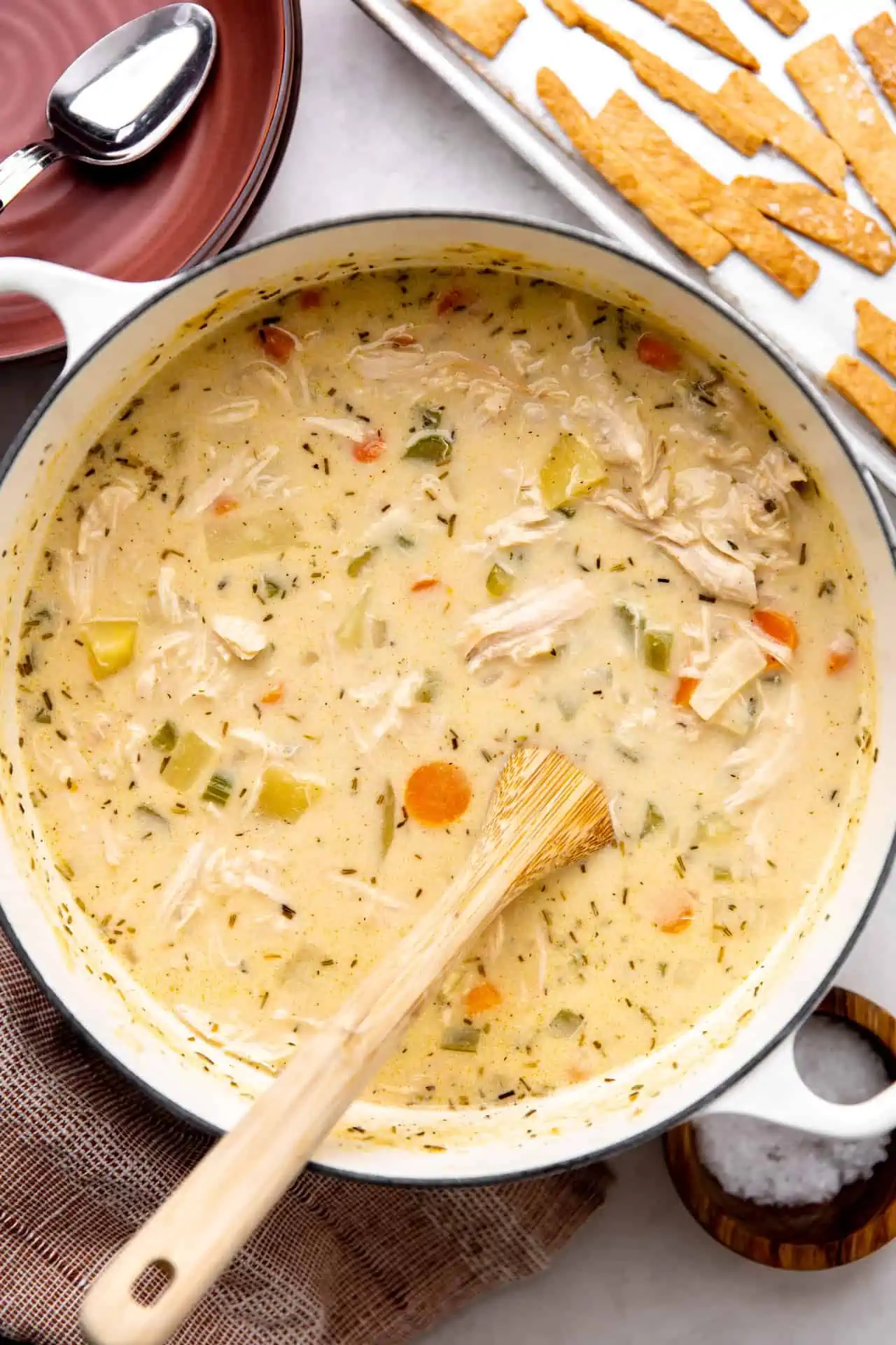Pot of pot pie soup with a wooden spoon.