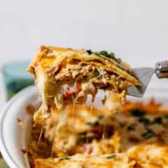Spatula serving a slice of king ranch chicken casserole showing melted cheese.