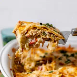 Spatula serving a slice of king ranch chicken casserole showing melted cheese.