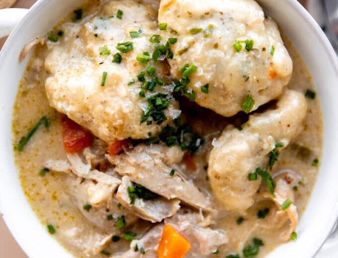 Bowl of chicken and dumplings topped with fresh chives.