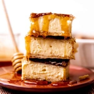 Stack of sopapilla cheesecake bars being drizzled with honey.