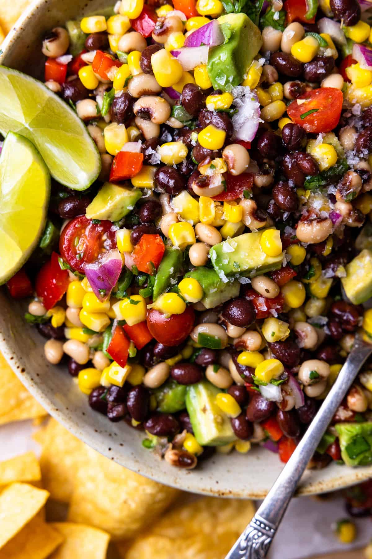 Up close view of Texas Caviar mixed with the dressing and garnished with lime wedges.