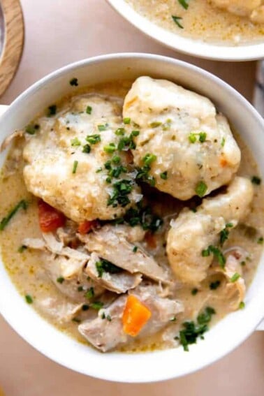 Bowl of chicken and dumplings topped with fresh chives.