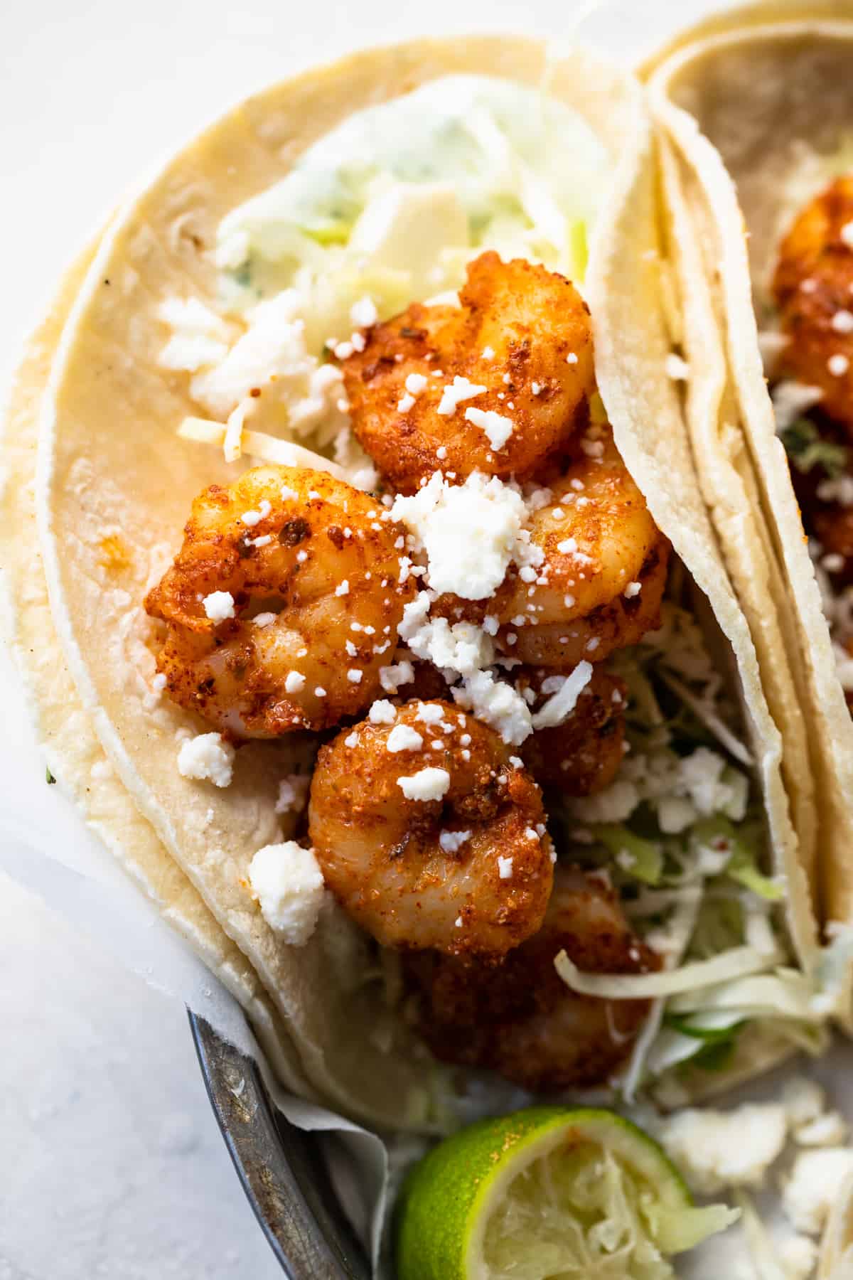 Corn tortillas filled with cabbage and taco seasoned shrimp. Topped with crumbled queso fresco and lime Crema. Lime wedges on the side.