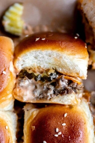 Up close cheeseburger slider on hawaiian rolls showing layers of ground beef, cheese, pickles and burger sauce.