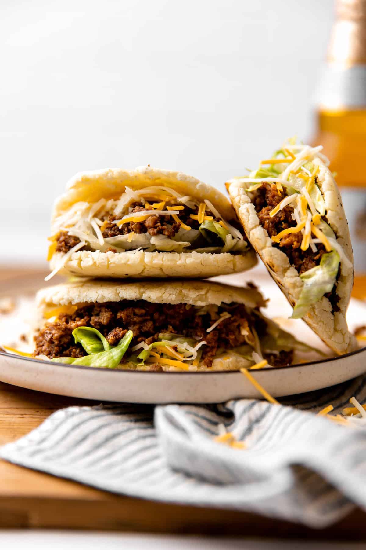 Stack of gorditas with ground beef filling with shredded lettuce and cheese.