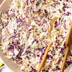 Bowl filled with a creamy southern coleslaw served with wooden spoons.
