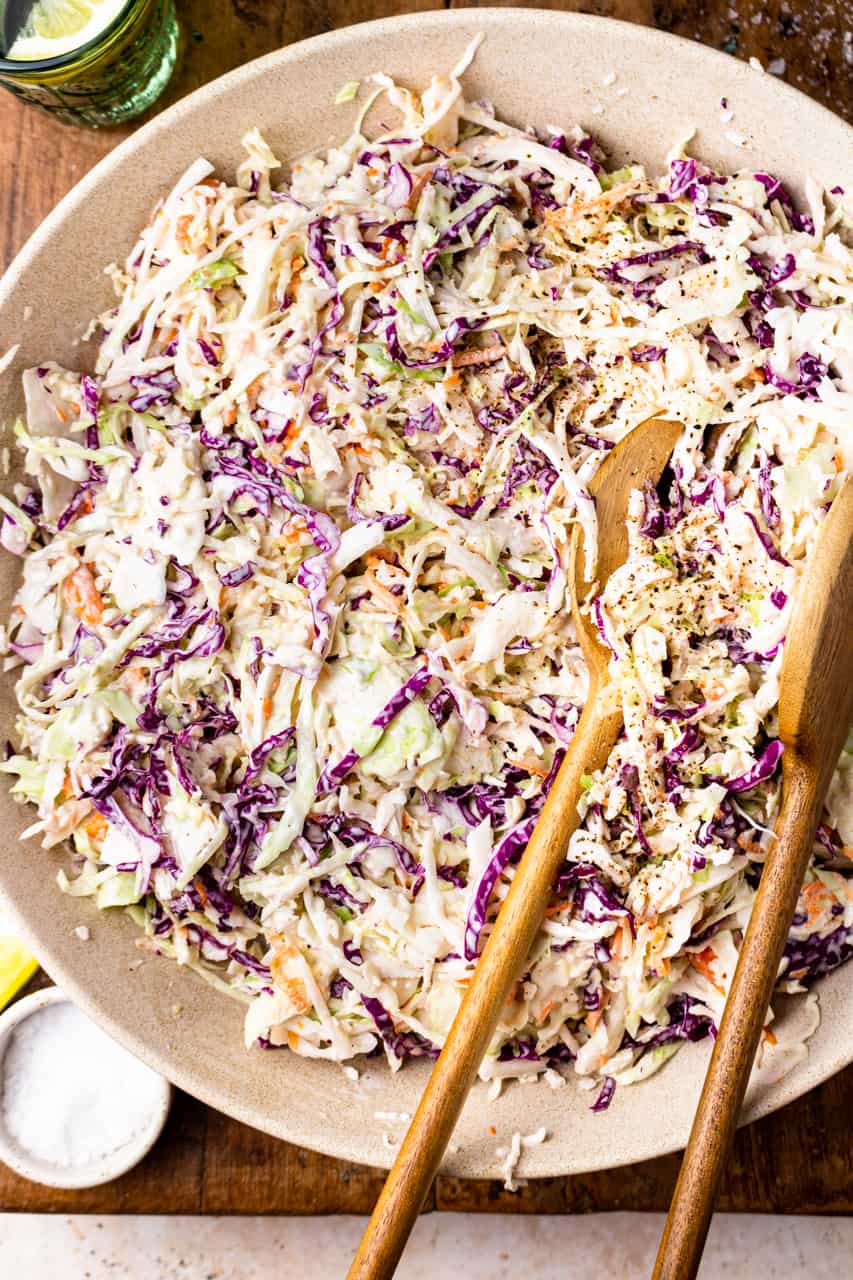 Bowl filled with a creamy southern coleslaw served with wooden spoons.