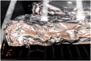 Ribs wrapped in foil in a smoker.