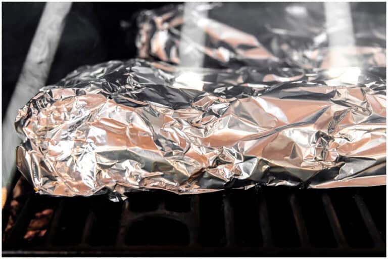 Ribs wrapped in foil in a smoker.