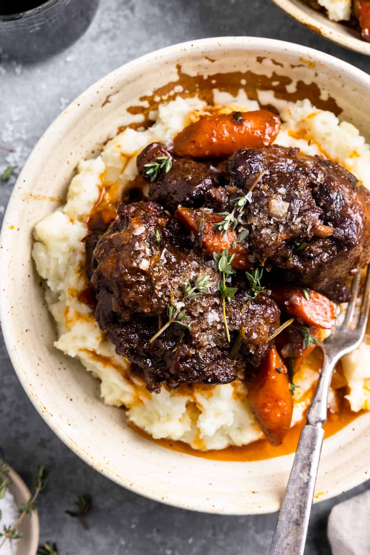 Plate with mashed potatoes, oxtails, and cooked carrots. 