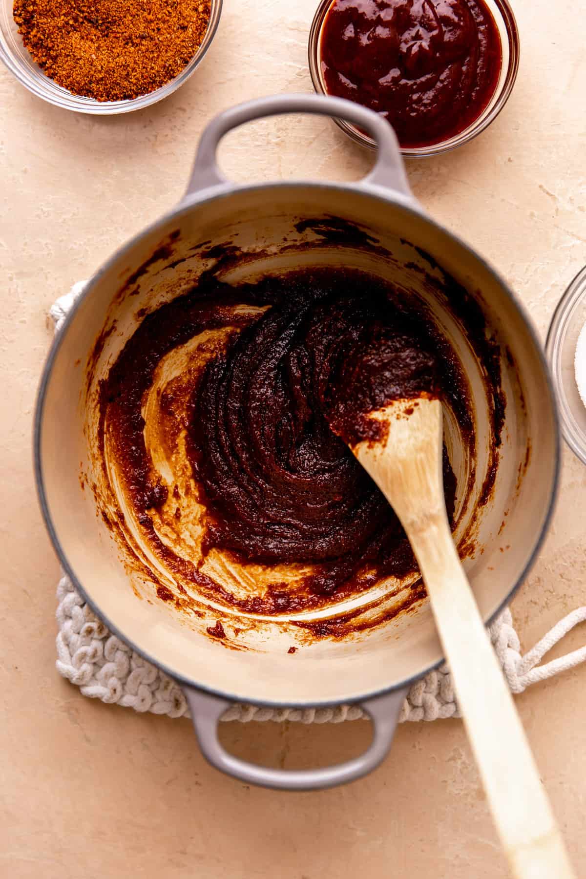 Small dutch oven with pulparindo candies melted and being stirred with a wooden spoon.