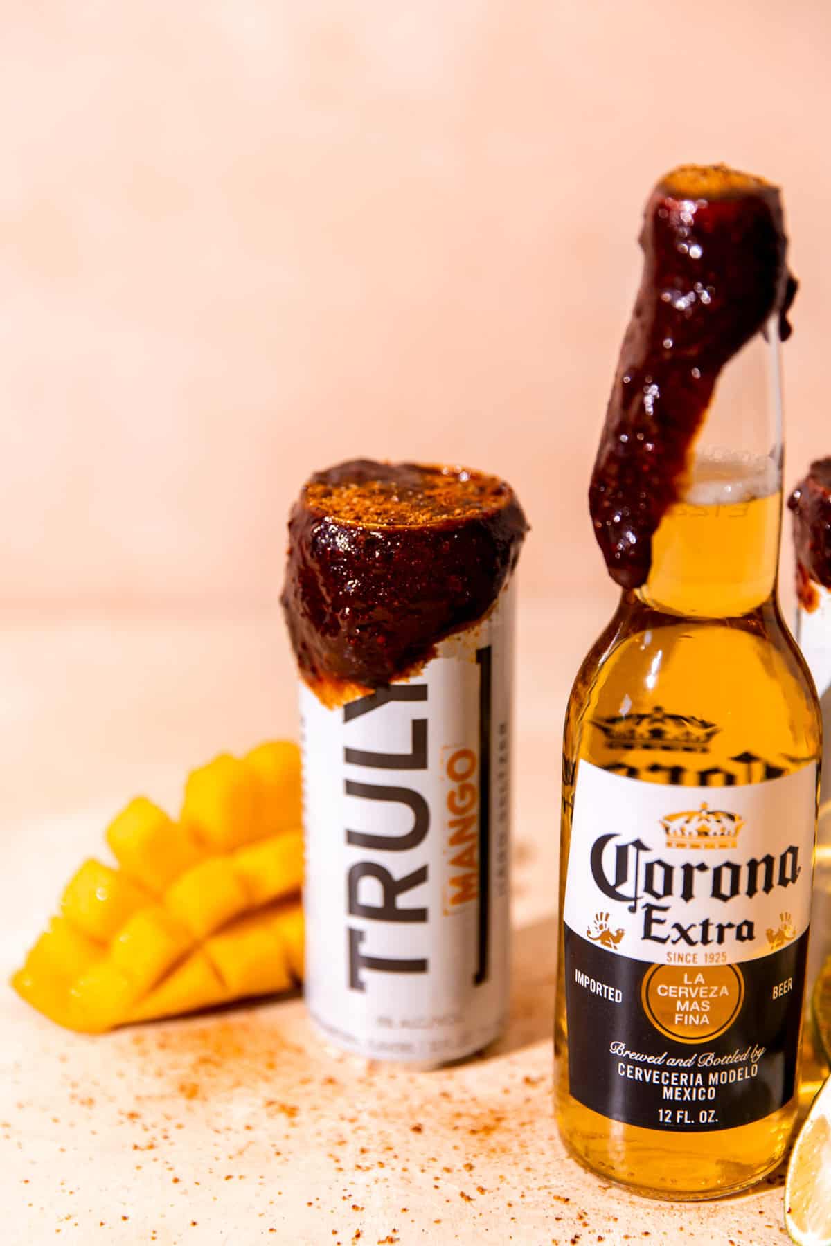 A can of hard mango spritzer with a chamoy rim and sprinkled with tajin, sliced up mango on the side. 