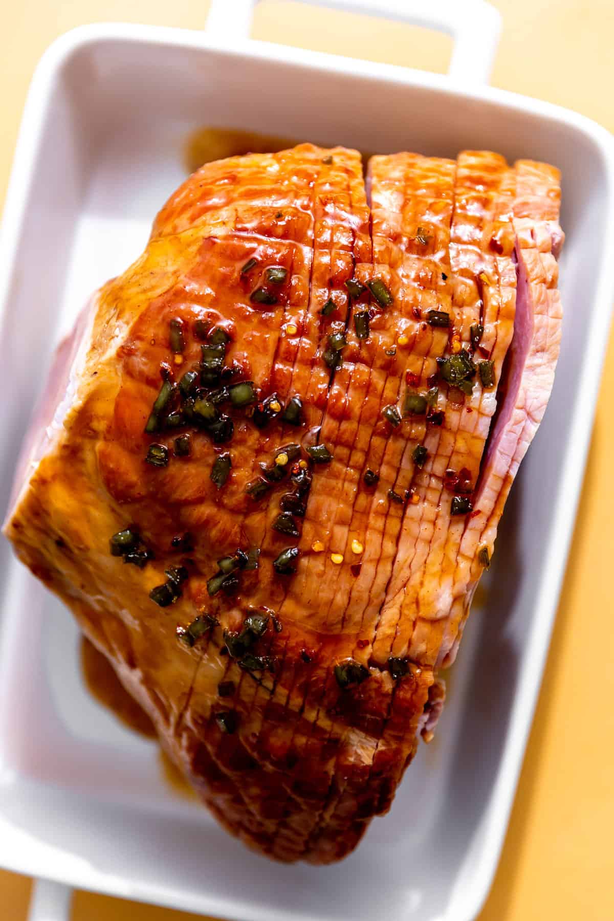 Ham in a large baking dish with jalapeno honey glaze on top. 