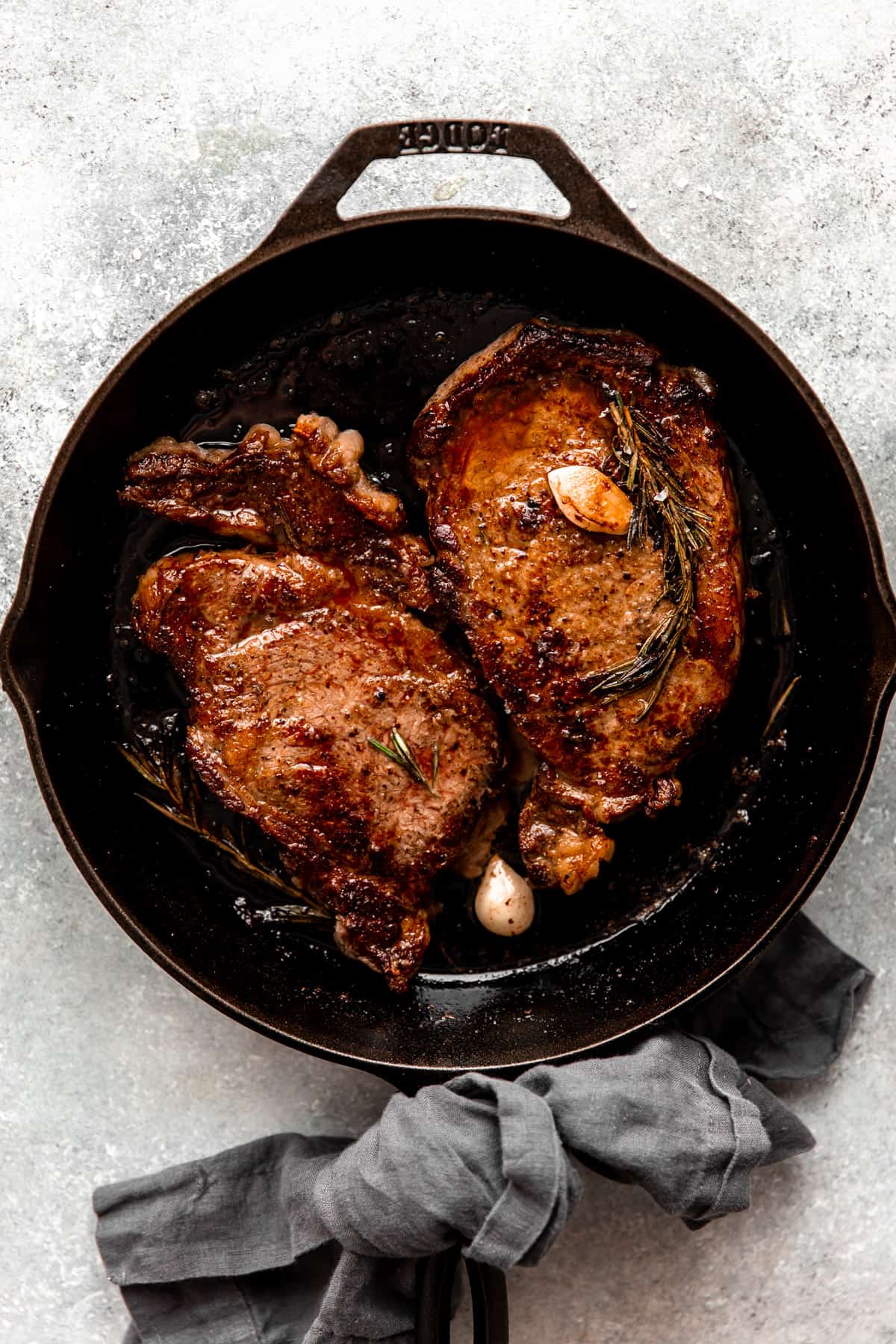 Cast iron skillet with ribeye steak, garlic and rosemary.