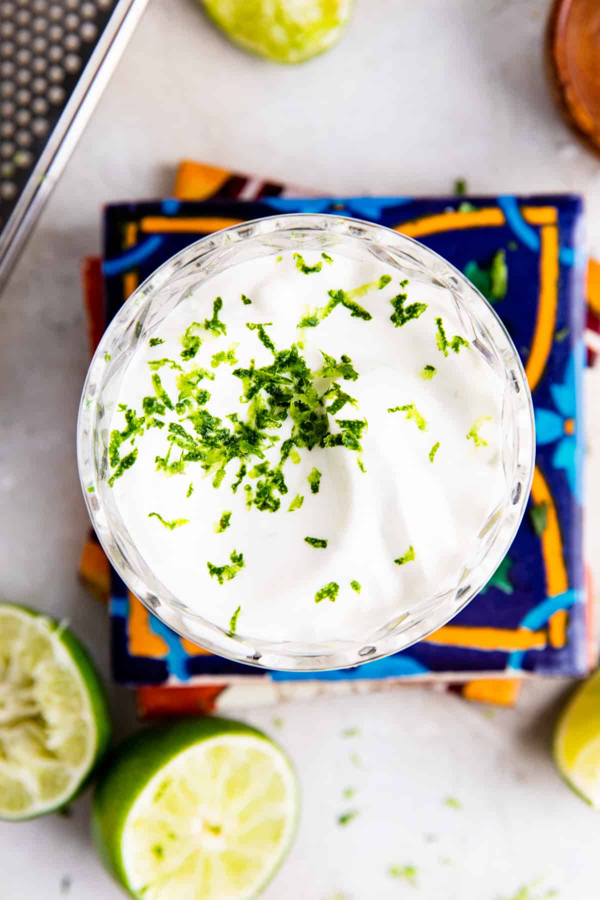 Glass filled with smooth Lime Crema topped with lime zest. Sitting on top of mexican tiles.