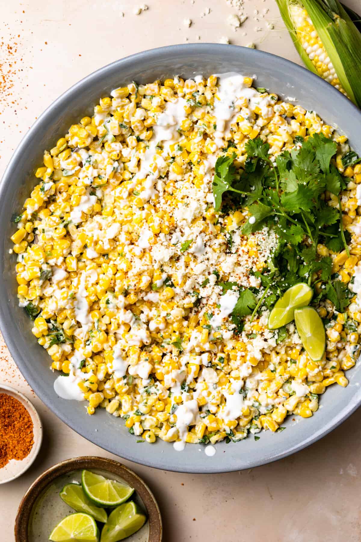 Mexican Street Corn Salad in a bowl topped with drizzled crema and crumbled cotija cheese. 