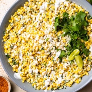 Mexican Street Corn Salad in a bowl topped with drizzled crema and crumbled cotija cheese.