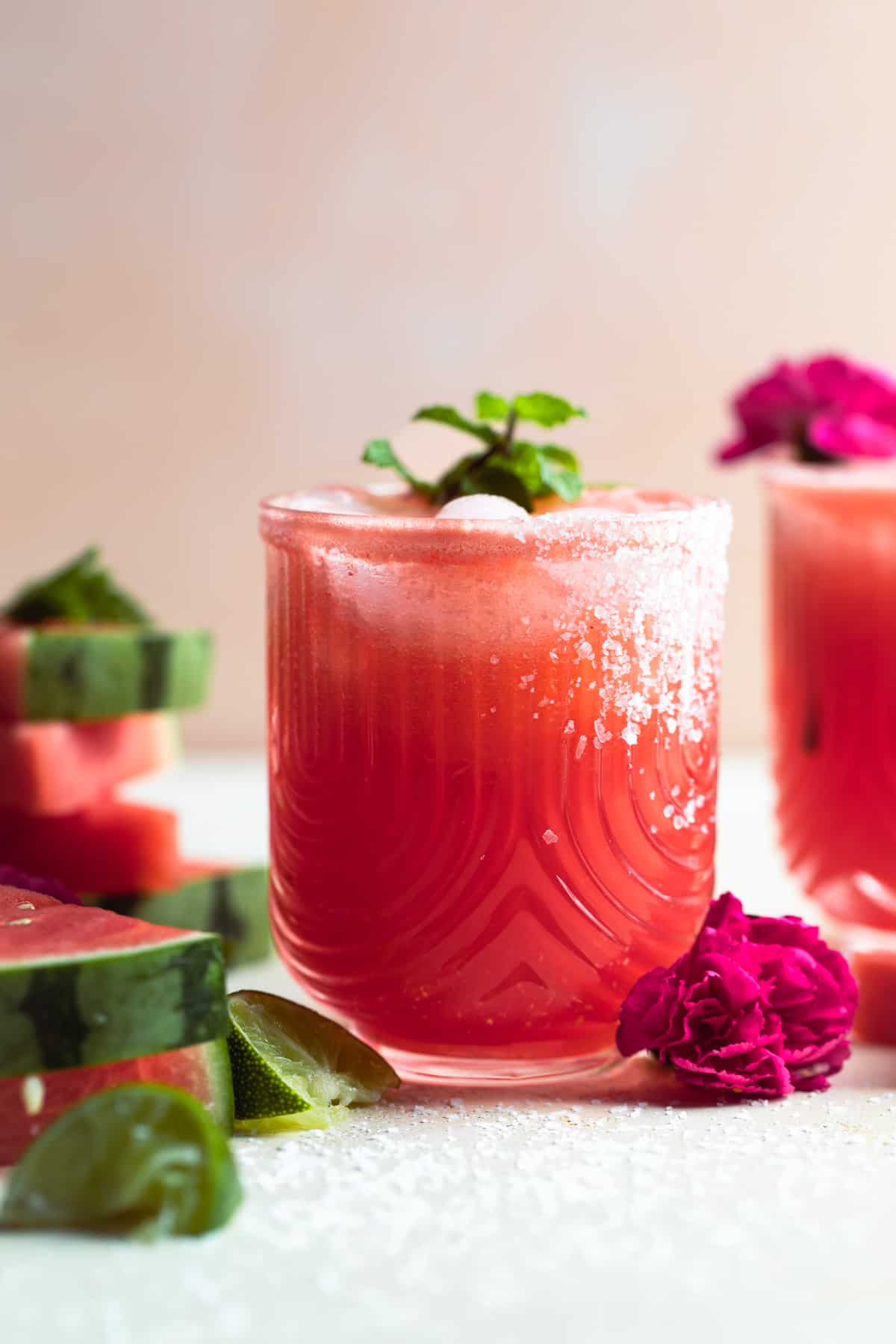 Glass filled with watermelon margarita and garnished with a sprig of mint.