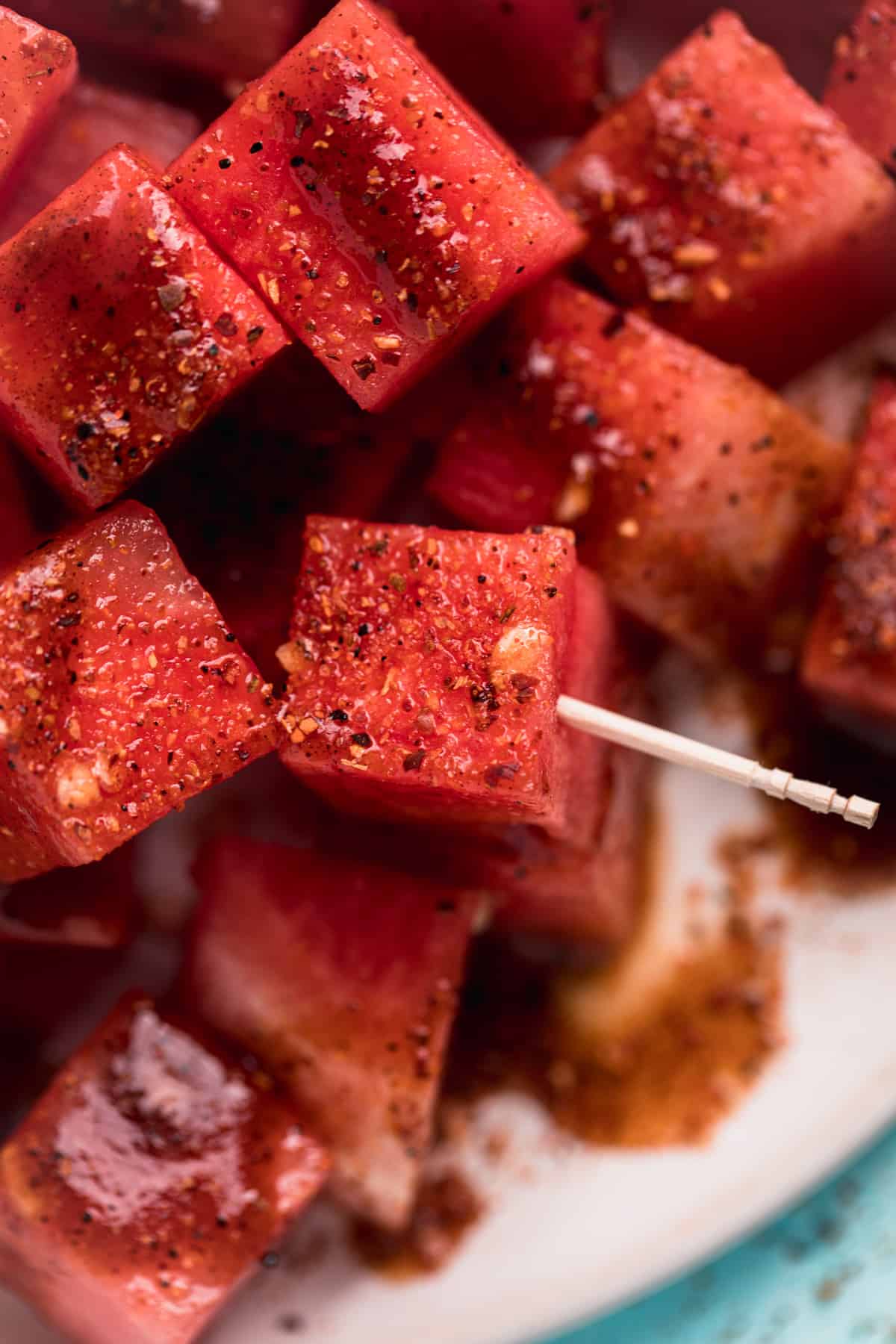Up close of cubed watermelon, chamoy and tajin with a toothpick for serving.