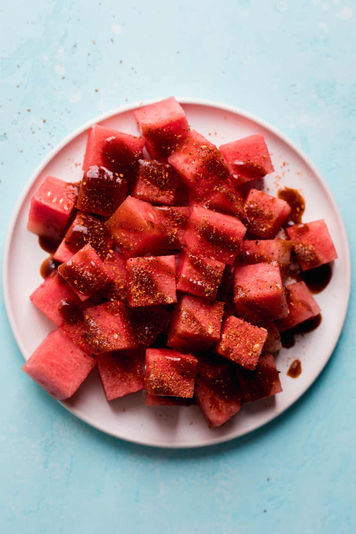 White plate with cubed watermelon, chamoy and tajin.
