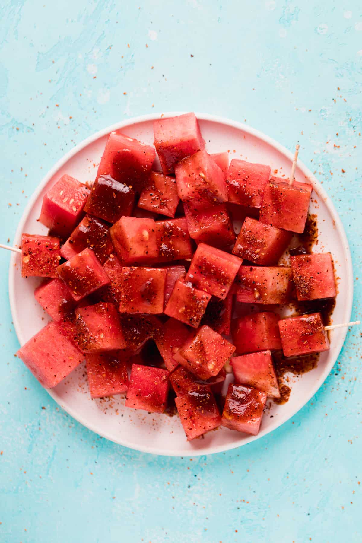Overhead view of white plate with cubed watermelon and tajin with chamoy.