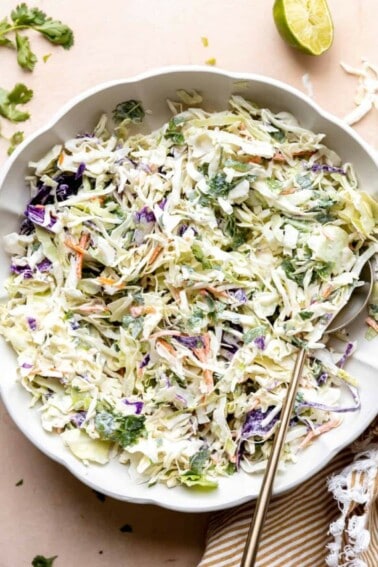 White bowl with creamy fish taco slaw made with red and green cabbage.