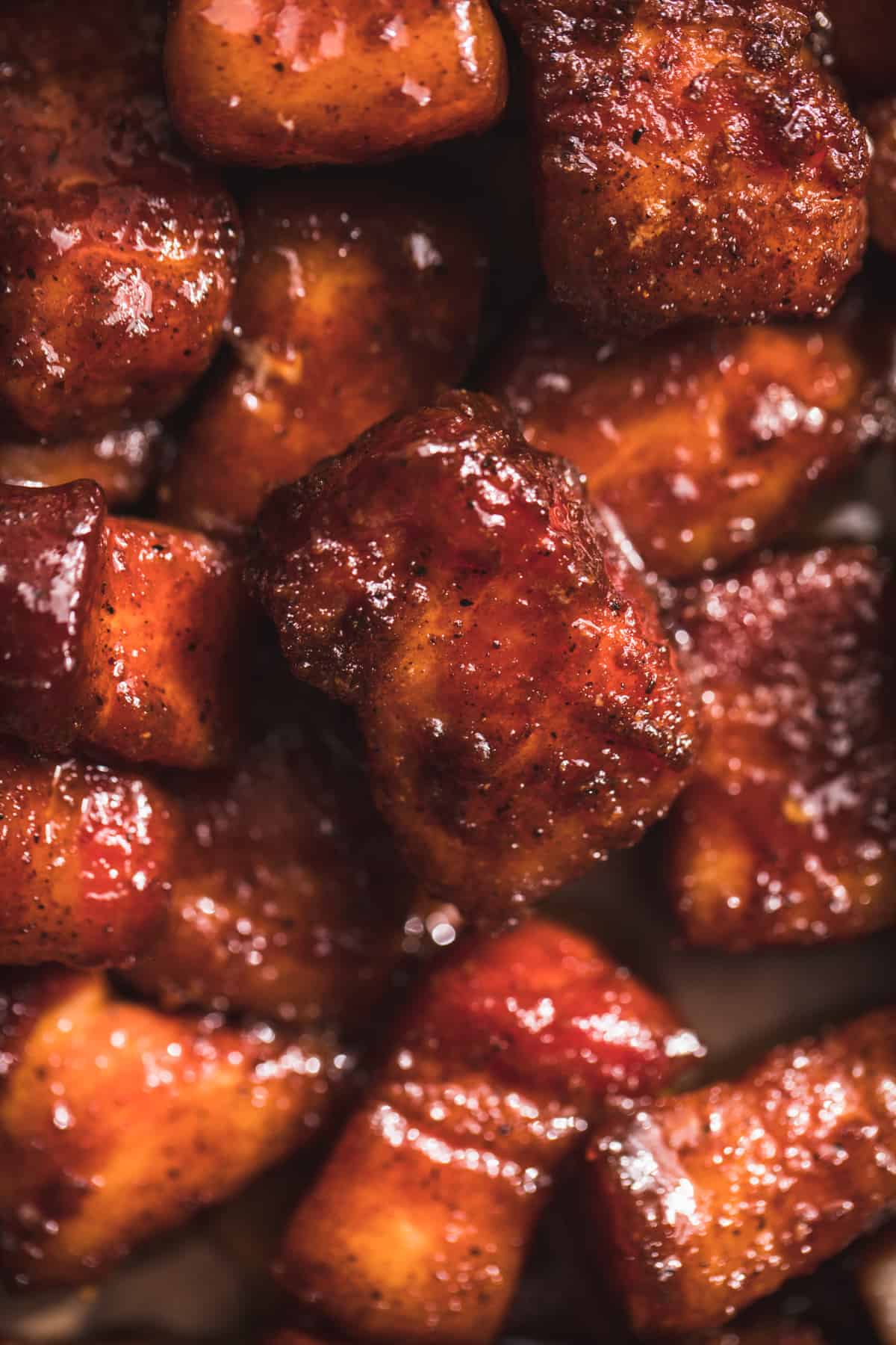 Up close view of pork belly burnt ends smothered in a sticky bbq sauce.