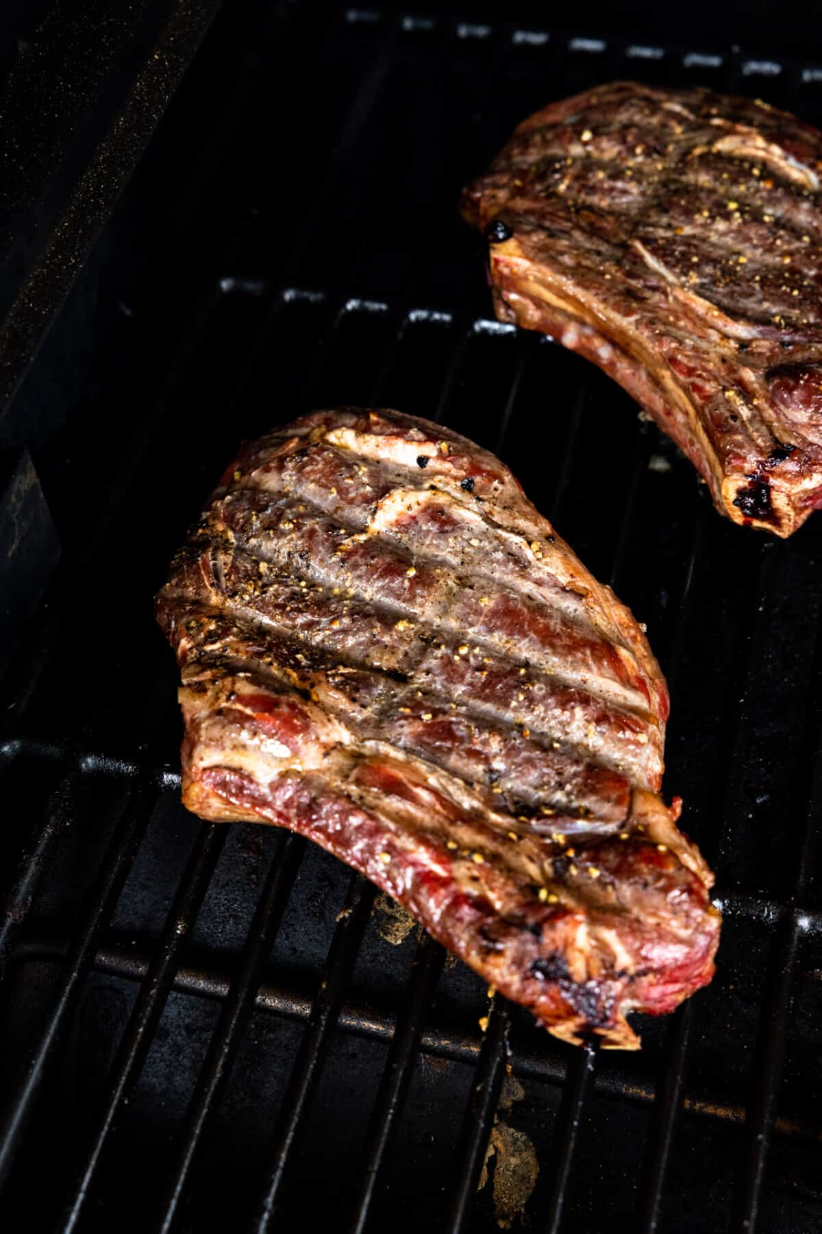 Ribeye steaks on a grill during smoking.