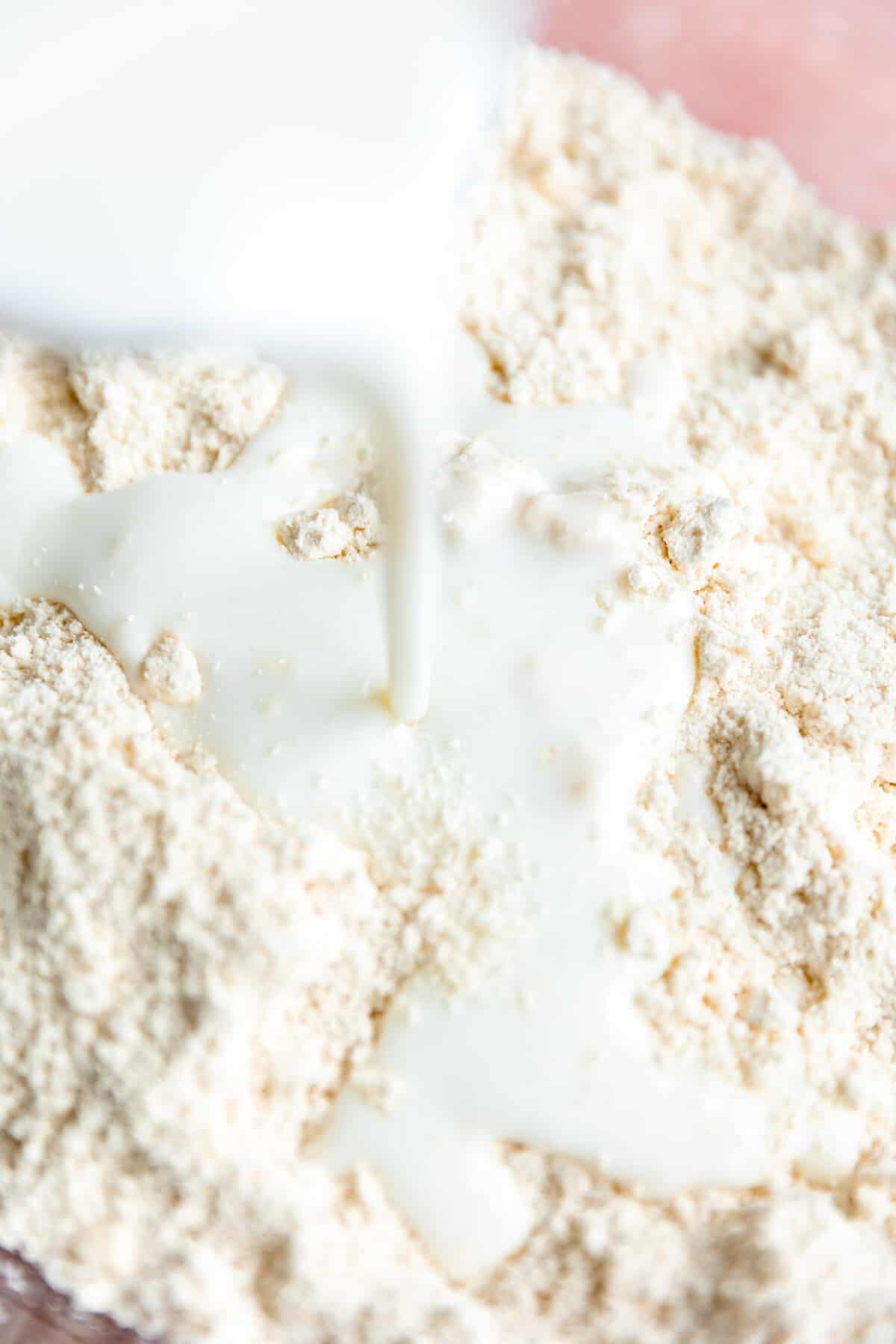 Buttermilk being poured into a bowl of flour.