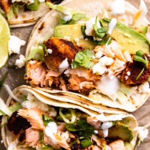 Salmon tacos topped with avocado and crema.