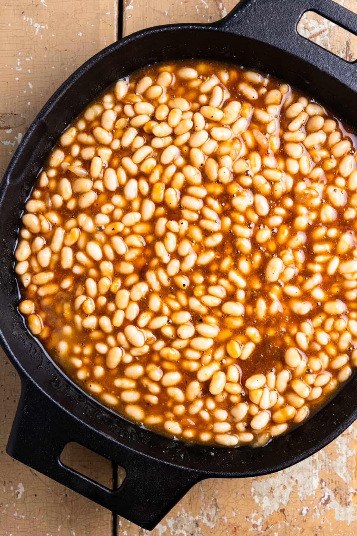 Baked beans in a cast iron skillet before cooking.