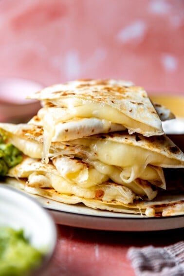 Stack of cheese quesadillas with melted cheese coming out the sides.