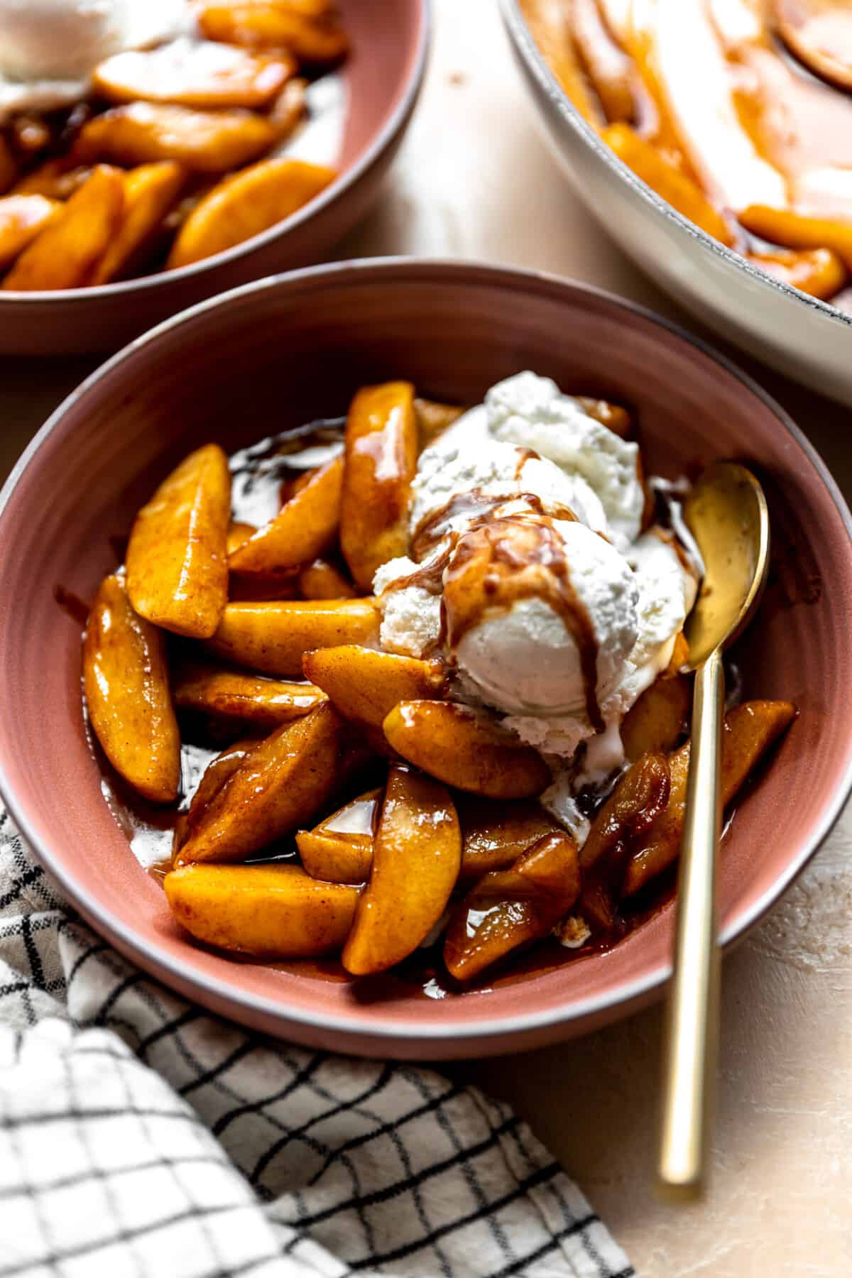 Bowl of fried apples topped with vanilla ice cream. 
