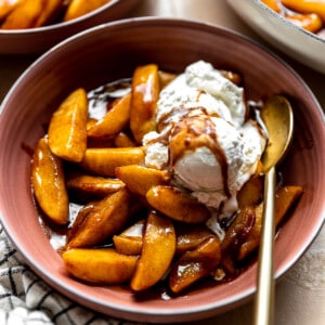 Bowl of fried apples topped with vanilla ice cream.