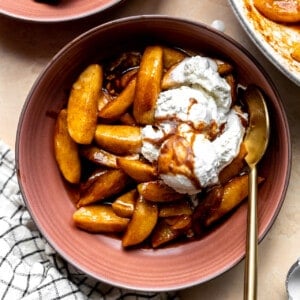 Overhead image of fried apples served in a bowl topped with a scoop of vanilla ice cream.