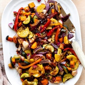 White plate filled with roasted mexican vegetables with a spatula for serving.