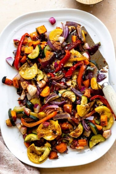 White plate filled with roasted mexican vegetables with a spatula for serving.
