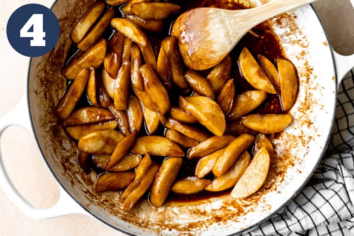 Fried apples in a skillet surrounded by a cinnamon spiced butter syrup.
