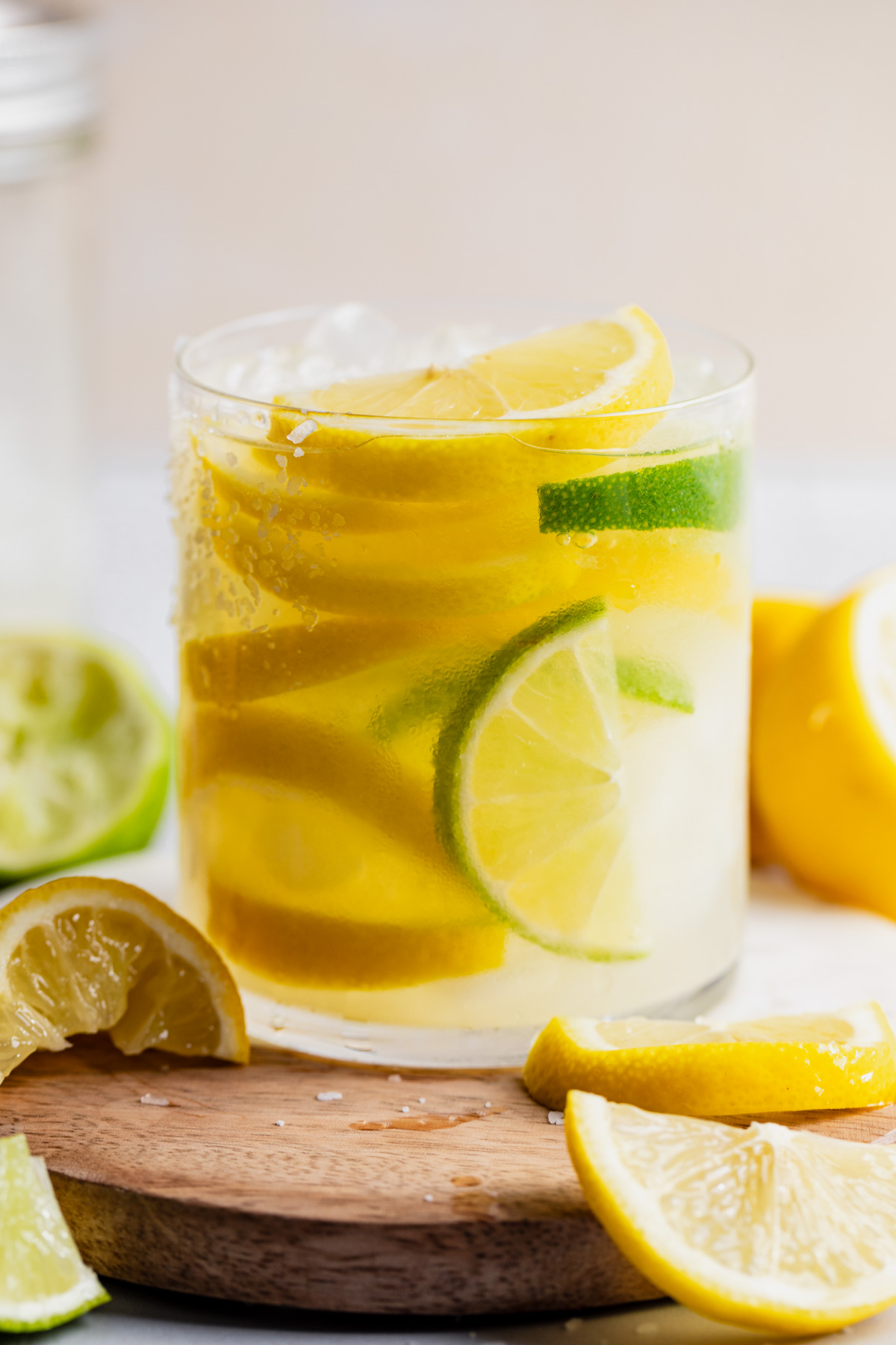 Up close of a glass filled with lemon slices, lime slices and lemon margarita. 