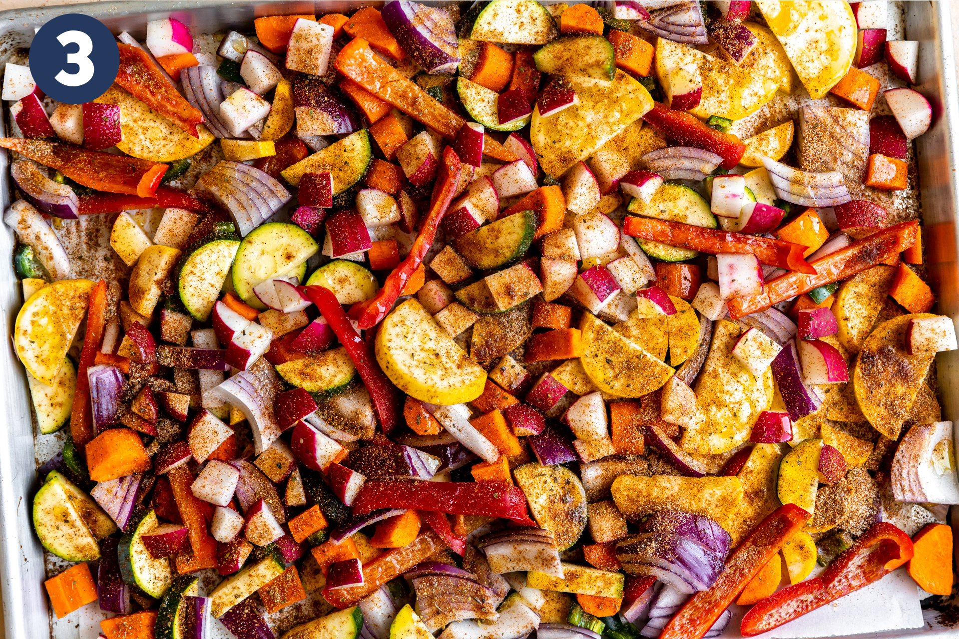 Sheet pan filled with raw vegetables coated in a homemade fajita seasoning. 