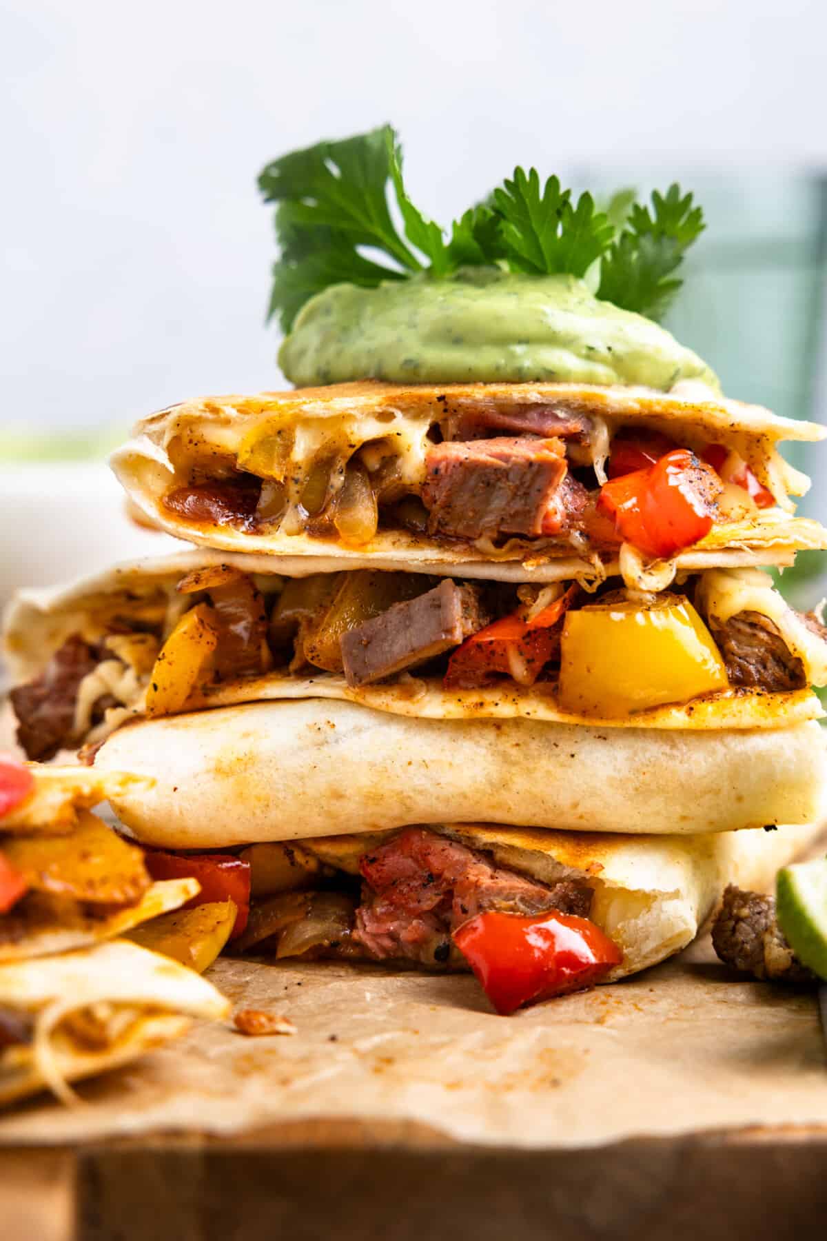 Up close look at a stack of steak fajitas topped with avocado crema, 