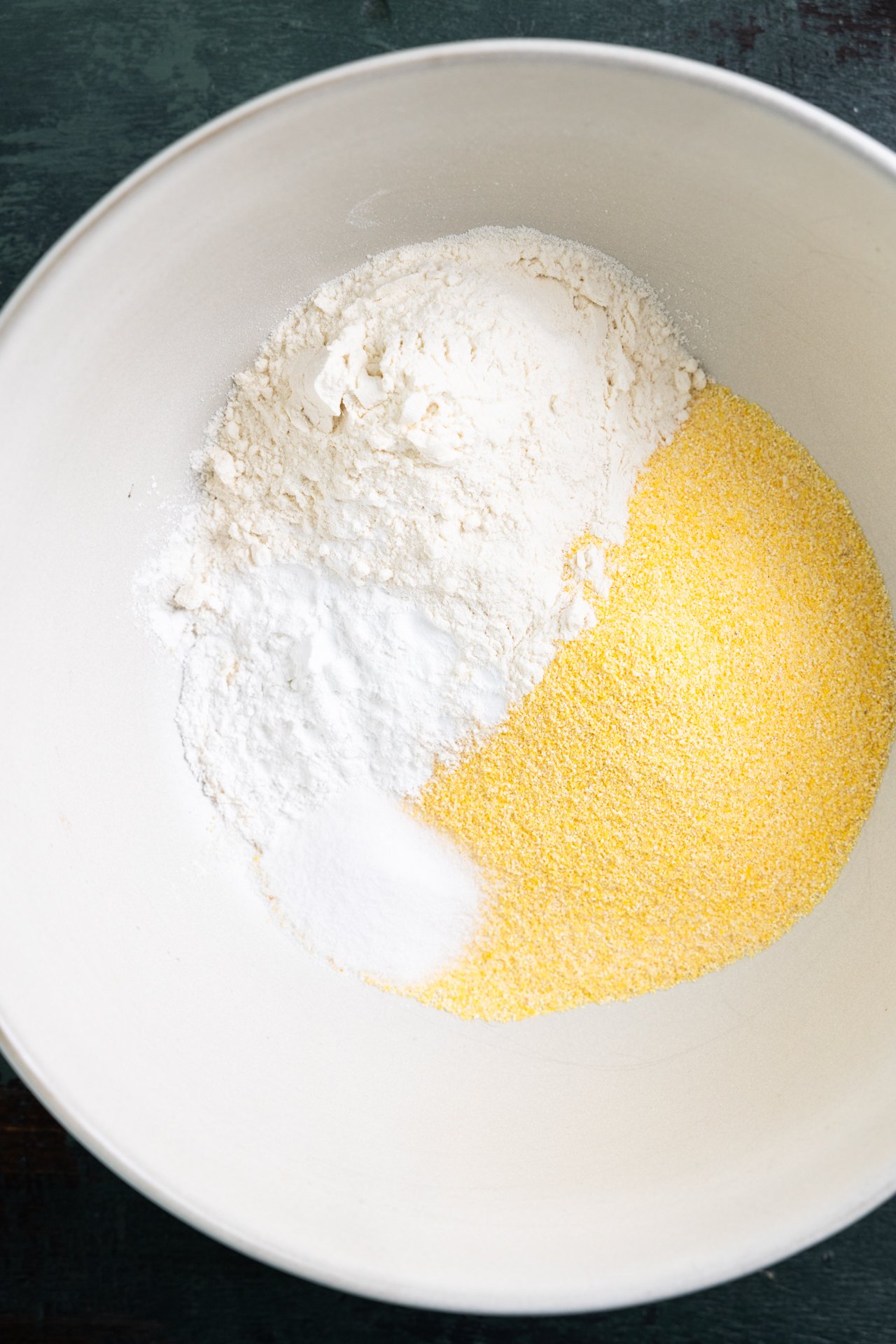 Dry ingredients of corn meal and flour in a white bowl. 