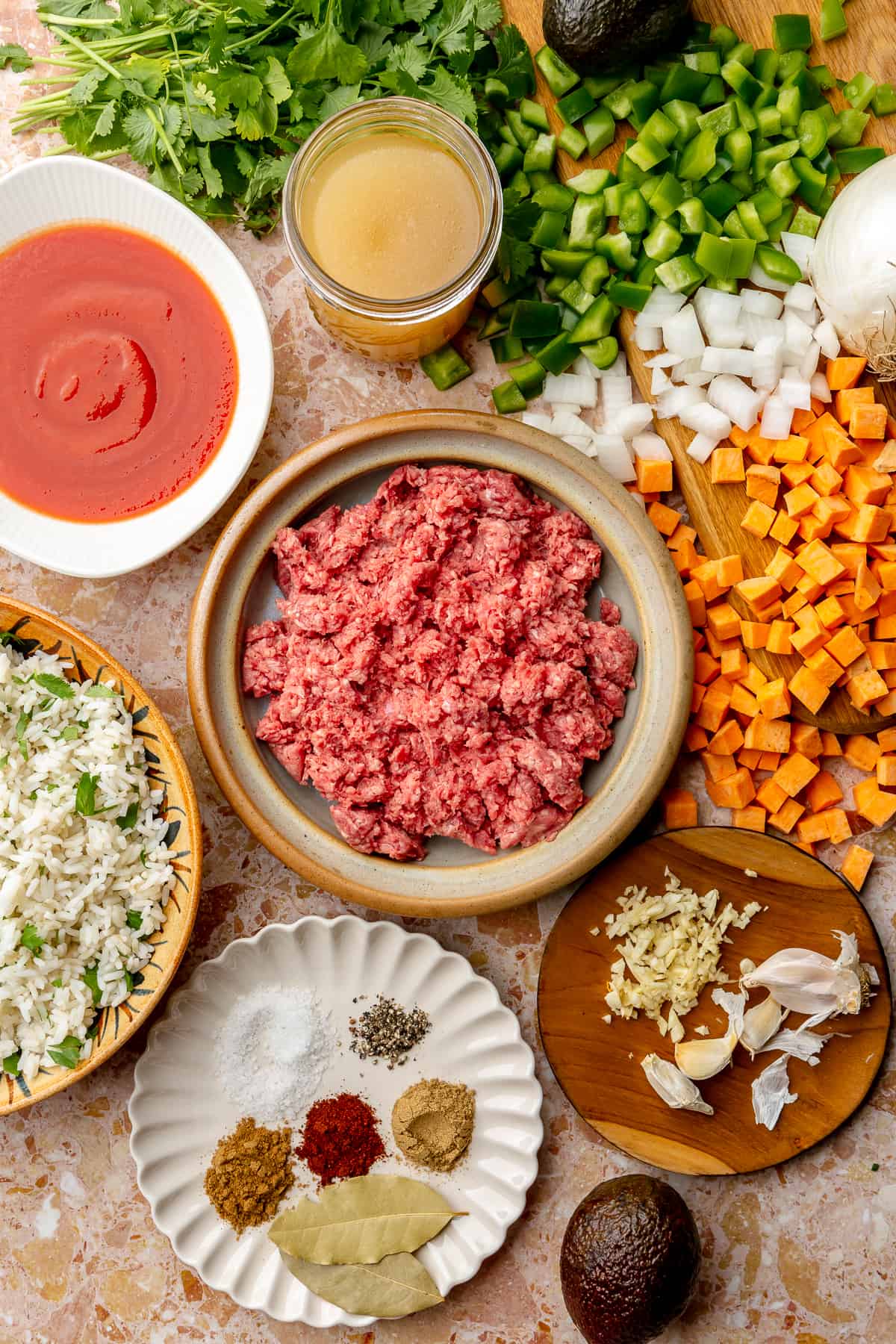 Ingredients needed to make a ground beef and sweet potato skillet meal laid out on the counter. 