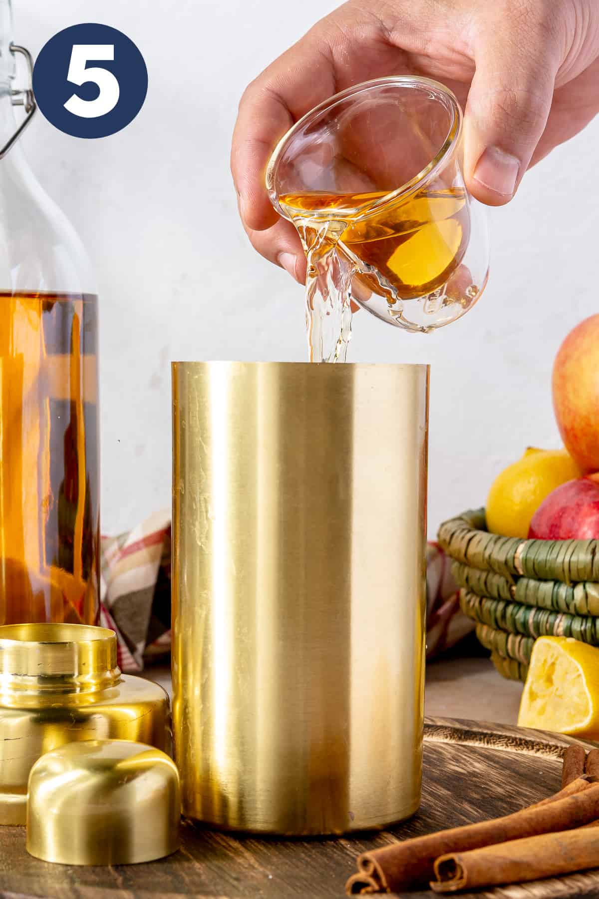Apple Cider being poured into a cocktail shaker. 