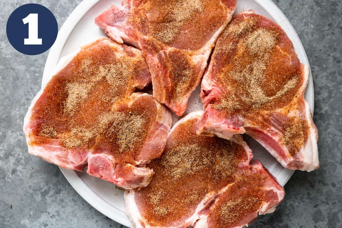 White plate with raw, seasoned pork chops for cooking. 