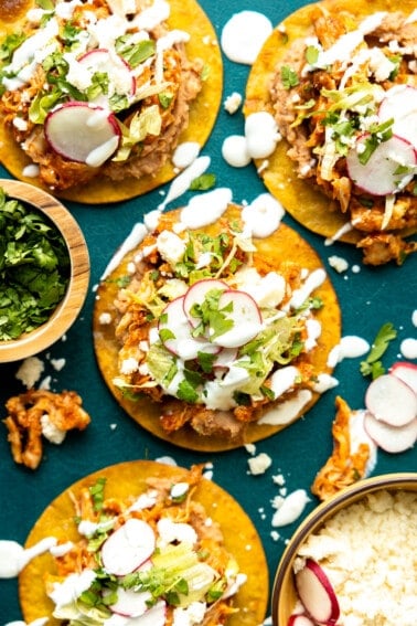 Tostadas topped with chicken tinga, drizzled with crema.