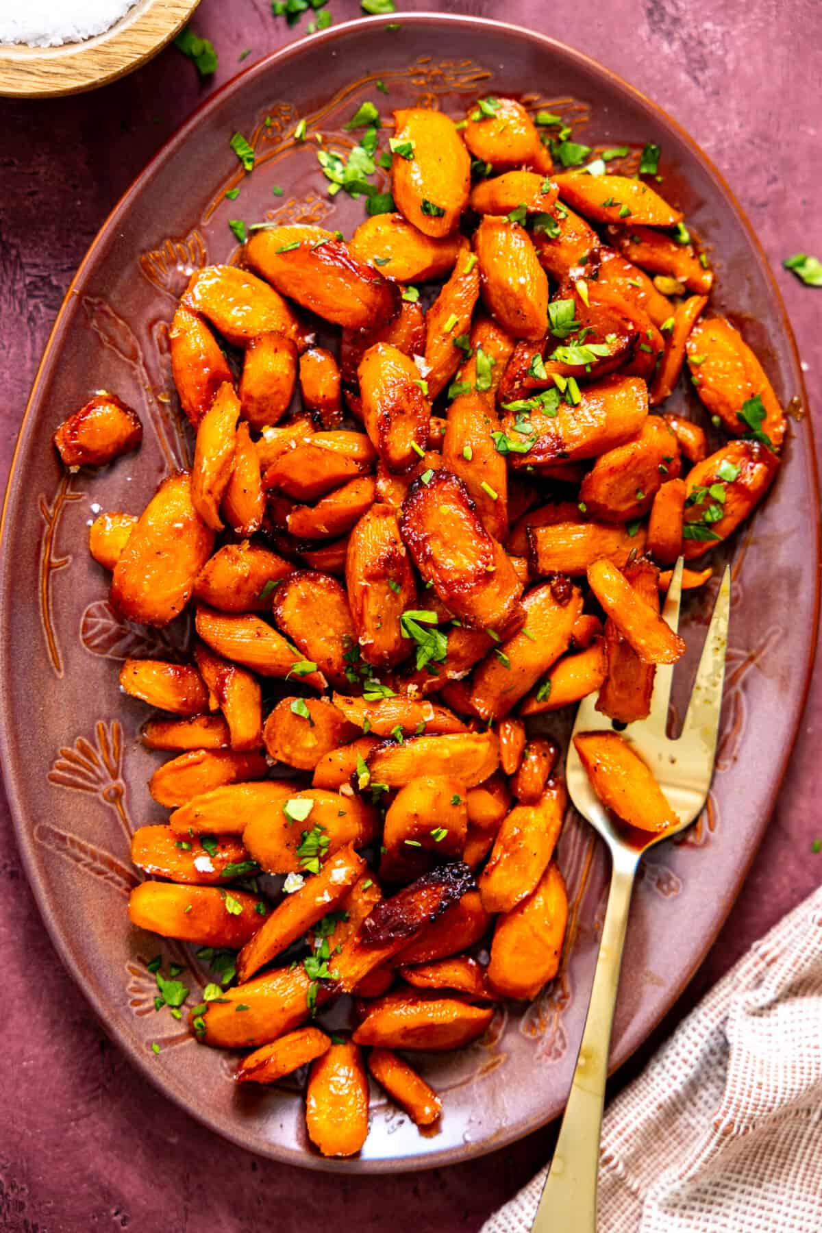 Dish filled with roasted carrots topped with fresh herbs. 
