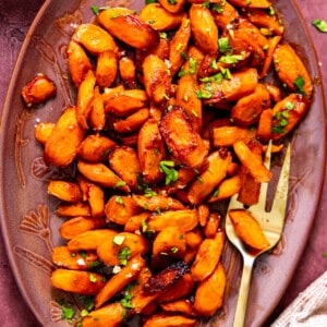 Dish filled with roasted carrots topped with fresh herbs.