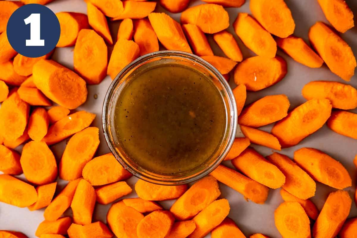 Bowl of honey mixture surrounded by sliced carrots. 